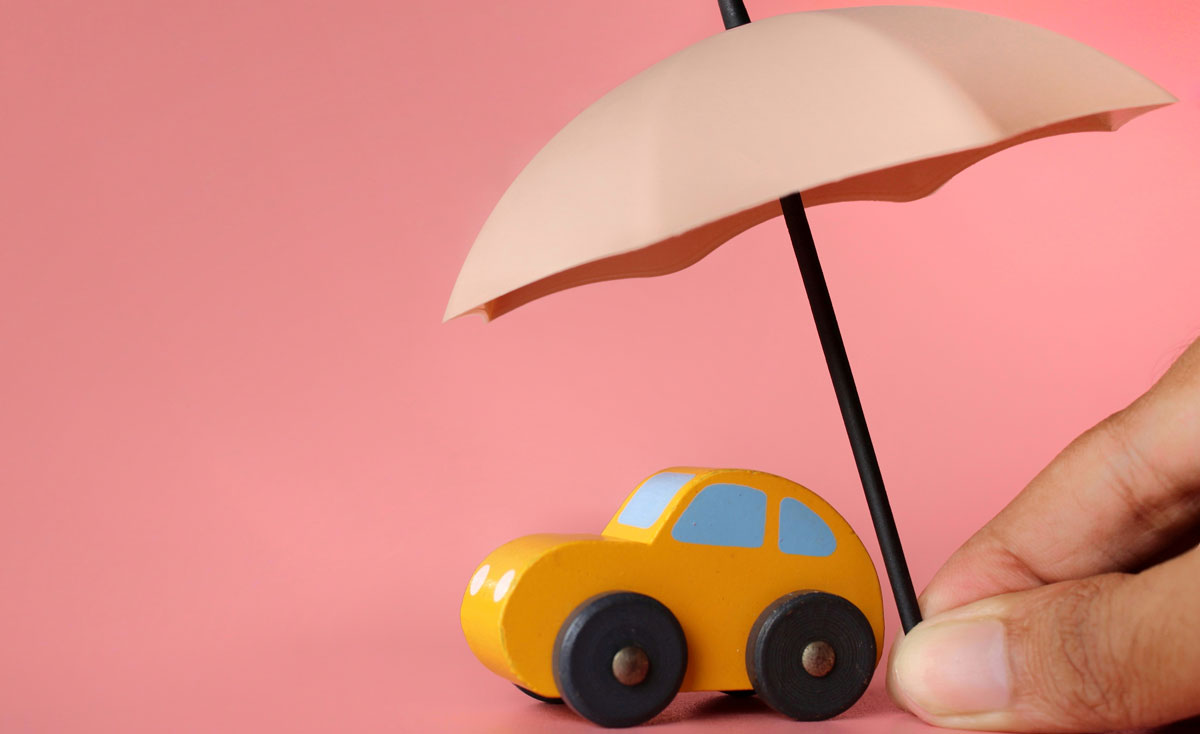yellow toy car under a pink umbrella with a flamingo colored background